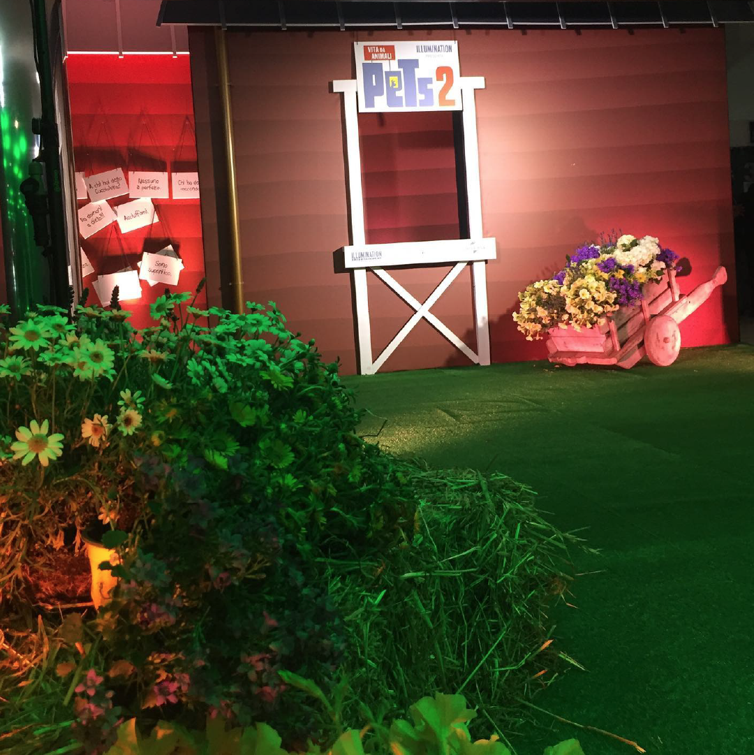 Allestimento per photo booth creato per la prima del film Pets 2. Nell'immagine è presente un prato, una casa di campagna la cui finestra è uno sfondo fotografico