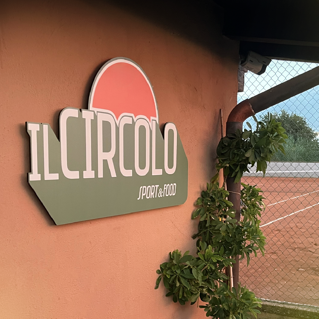Insegna di "Il circolo food & sport" appesa sul muro esterno dell'edificio con affaccio sui campi da tennis